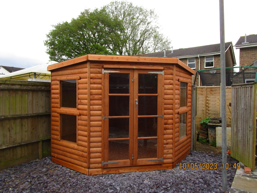 Wooden garden shed with glass panel windows and doors surrounded by fencing in a backyard setting